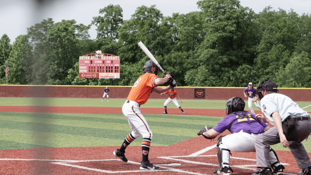 A baseball player in action, swinging a bat to hit the ball on a green field under bright stadium lights.