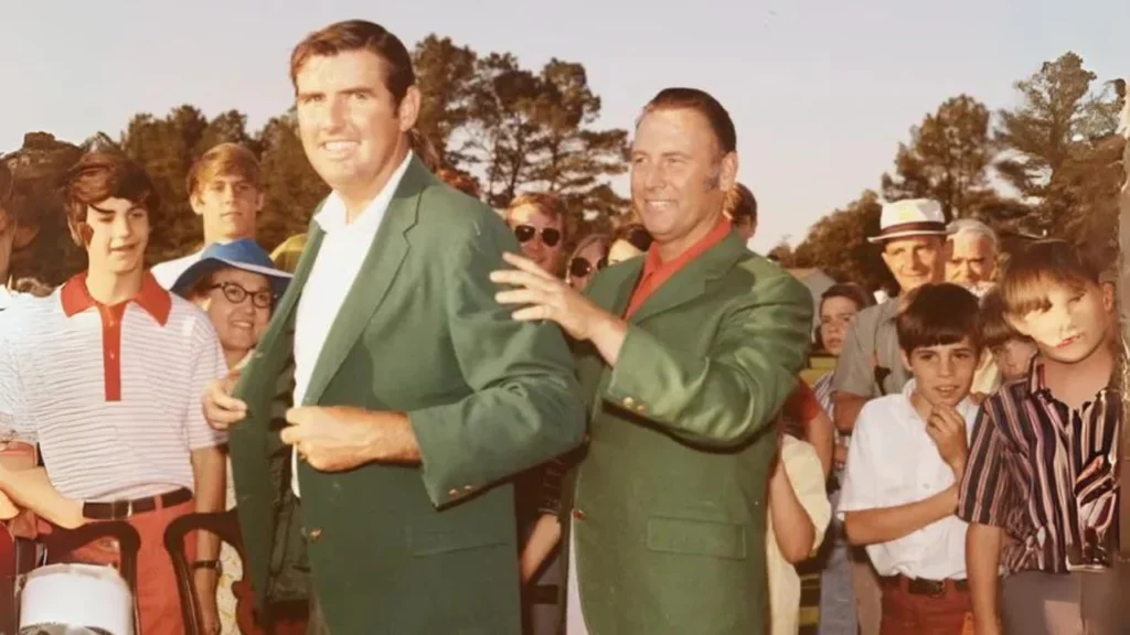 At the ceremony to award the Green Jacket, Charles Coody, the 1971 Masters Champion, is helped by Billy Casper (right). 

