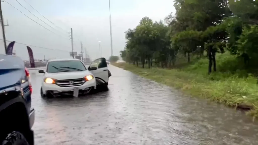 In this screenshot from a social media video, a driver who got stuck gets out of their car on a flooded road near Houston, Texas, on May 2, 2024.
@StormChaserHTX