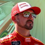 Michael Annett standing beside his NASCAR race car during a pre-race event.